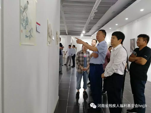 图为常为民副理事长（左二）、刘杰主席（左一）参观残疾人画家王璐作品